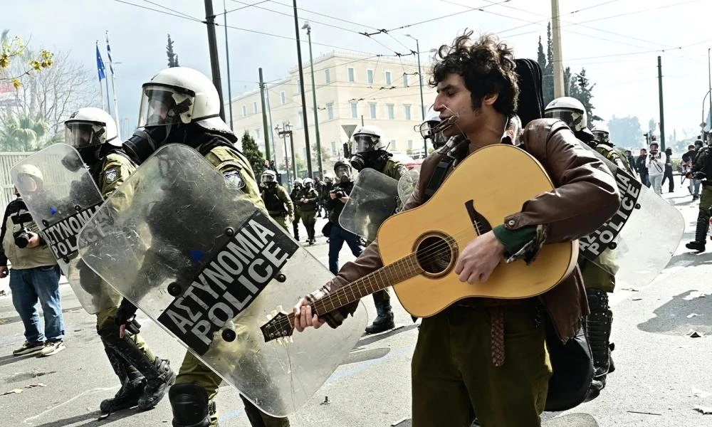 Διαδηλωτής παίζει κιθάρα δίπλα στα ΜΑΤ τη στιγμή των επεισοδίων